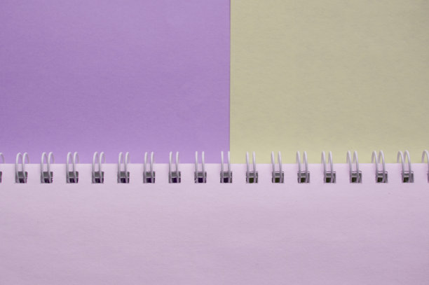 打开空的螺旋笔记本，以淡紫色和灰色的两种色调为背景，俯视图，极简主义与一份空间与一张空白纸平躺在桌子上图片下载