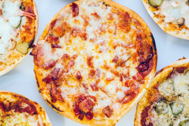 新鲜烤辣香肠披萨。芝士披萨片背景。热披萨与融化的奶酪。食品的背景。图片为模板，标语牌，横幅。图片下载