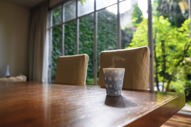 晨光中，热气腾腾的咖啡杯坐在餐桌上图片下载