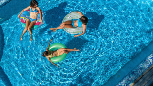 家庭在游泳池空中无人机从上面看，快乐的母亲和孩子游泳在充气圈甜甜圈和有乐趣的家庭度假，热带度假度假胜地图片下载