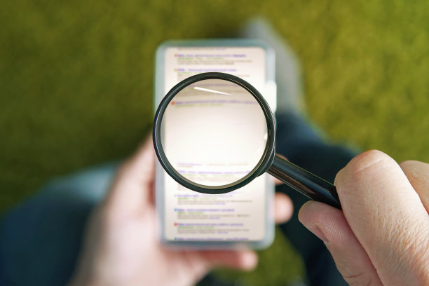 坐在上面的男人拿着透明放大镜在智能手机上浏览搜索引擎页面。在移动屏幕上方的放大镜中心复制你的文字空间。使用手机上网的概念。图片下载