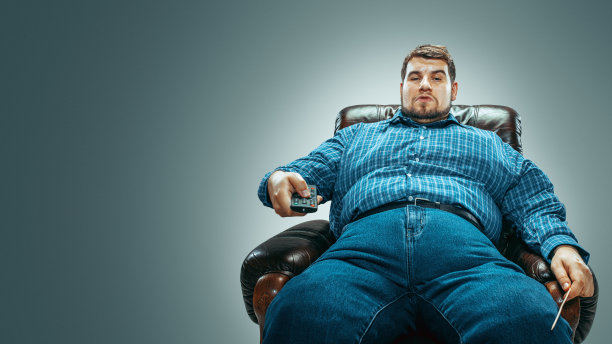 胖子坐在棕色的扶手椅上，情绪激动地看电视图片下载