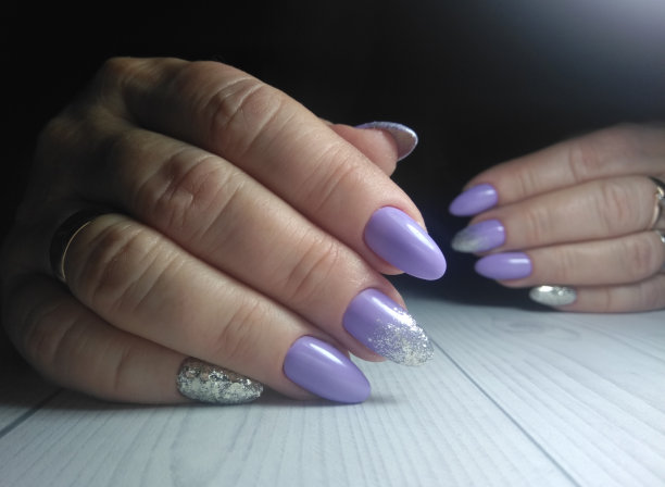 女人的指甲长而圆。凝胶漆配亮片紫色细腻。淡紫色饰面带有银色薄片设计图片下载