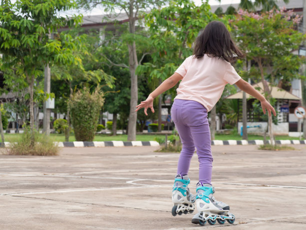 玩旱冰的亚洲女孩。户外活动。的背后。图片下载