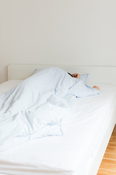 一个男人睡在白色的床上图片下载