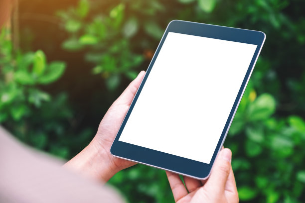 公园里，一名女子手持黑色平板电脑，桌面屏幕是空白的图片下载