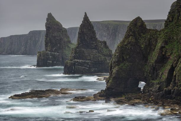 这是一张慢速快门的照片，展示了在一个多云的夜晚，英国苏格兰约翰奥格罗茨附近的杜肯斯比岬的悬崖上，海浪撞击海波的运动。图片下载