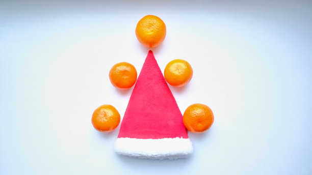 圣诞橘子在白色的背景下围着一顶红色的圣诞帽图片下载