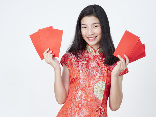 2020年中国新年。身着中国传统旗袍的年轻女子手持白色背景上的红包图片下载