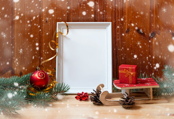 白色相框，圣诞球和木制雪橇上的礼物木制桌子。图片下载