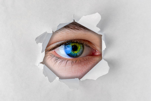 近距离观察的眼睛透过撕纸洞图片下载
