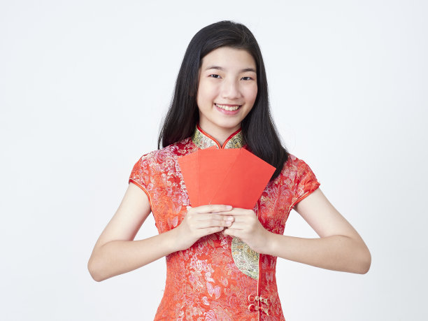 2020年中国新年。身着中国传统旗袍的年轻女子手持白色背景上的红包图片下载