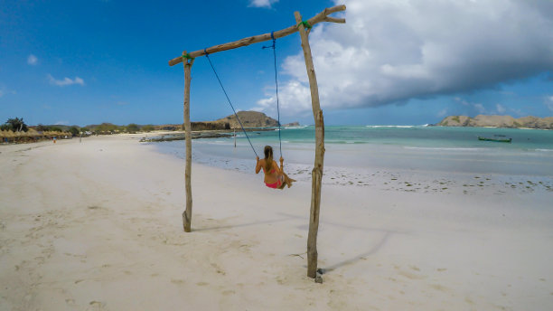 龙目岛-在海边的木秋千上荡秋千的女孩图片下载