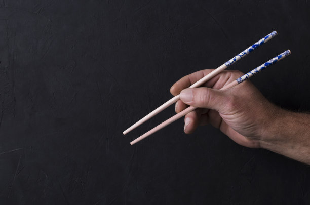 男子使用传统木筷子，背景暗。设计空白图片下载