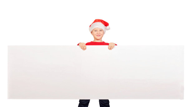 一个可爱的小孩的圣诞模型，十几岁的男孩戴着圣诞帽和红色毛衣孤立在白色的背景。圣诞假期。男孩指着他的手。图片下载