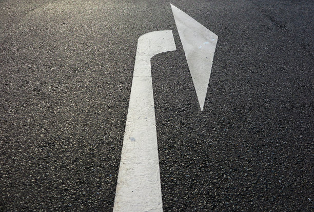 靠近孤立的白色箭头在柏油路显示正确的方向-德国图片下载