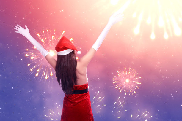 一个亚洲女人在圣诞老人服装看烟花的后视图图片下载
