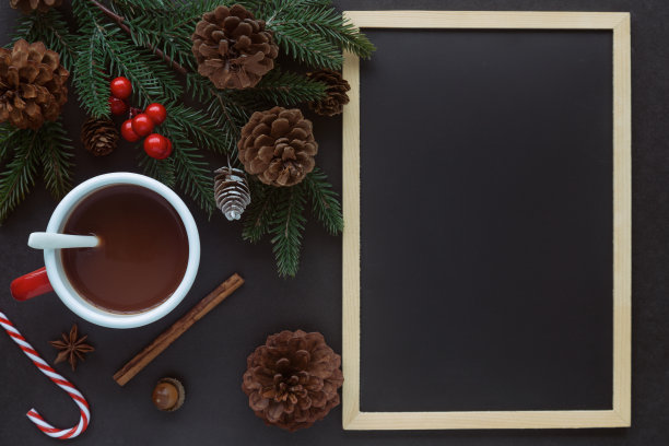 黑色花岗岩桌子装饰黑板或黑板，松叶，锥和巧克力杯的圣诞概念。背景在俯视图平铺与圣诞墙纸复制空间。图片下载