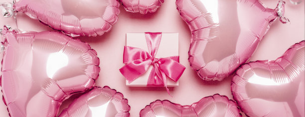 礼物和粉红色的心形气球在粉红色的背景。概念情人节，装饰，婚礼，邀请或照片区。箔球。横幅。平躺，俯视图图片下载