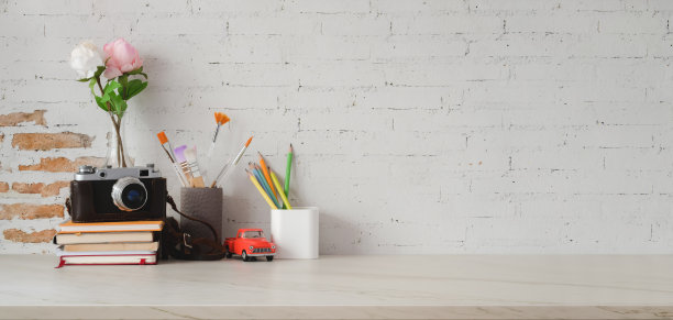 在大理石桌子和砖墙上用相机和办公用品拍摄复古的工作场所图片下载