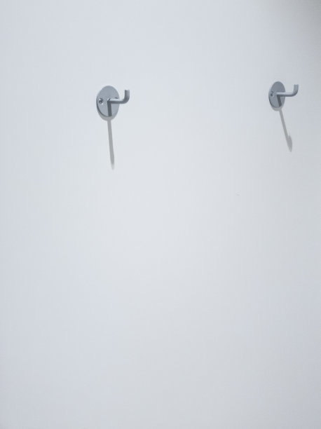 有复印空间的白墙上挂着两个衣服挂钩图片下载