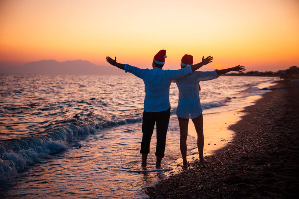 一对在海滩上戴着圣诞帽的幸福夫妇图片下载