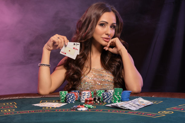 女孩在赌场玩扑克。拿着牌，坐在堆满筹码和钞票的桌子旁。黑色，烟雾背景，彩色的背光。特写镜头图片下载