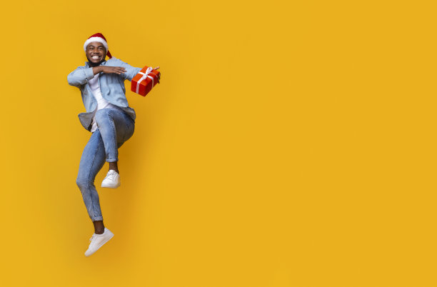 兴高采烈的黑人拿着礼盒，在空中跳了起来图片下载