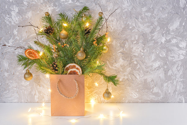用冷杉枝装饰的冬季节日花束、金球、干橙和灯光灯花环等工艺包放在桌子上与拷贝空间。概念圣诞节或新年，可选择圣诞树图片下载