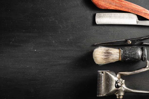 美发剪刀，老式手工剪，梳子，刷子，危险的剃须刀，都在一个上有黑色灰尘的表面上。图片下载