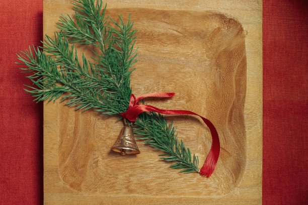 金色的圣诞钟声和冷杉树枝在一个质朴的木制背景。新年快乐。图片下载