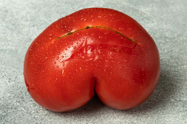 一个红色心形番茄在灰色背景上图片下载