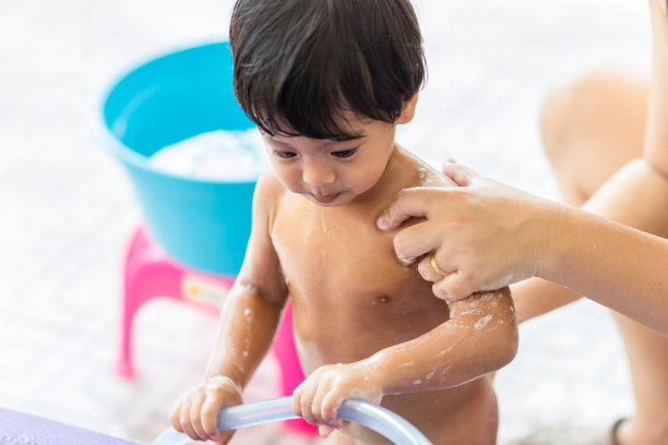 可爱的新生婴儿该洗澡了。刚出生的男婴正在洗澡。妈妈用海绵清洁婴儿的头发。亚洲新生儿正在洗澡，由母亲。图片下载