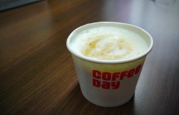 在棕色的木质办公桌上放一杯用烘培咖啡豆制成的卡布奇诺咖啡，庆祝办公室和家里的浓咖啡日。图片下载