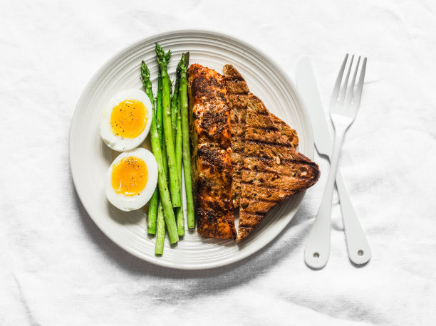 健康饮食午餐-烤鲑鱼，煮软蛋，芦笋和全麦面包在一个轻的背景，俯视图图片下载