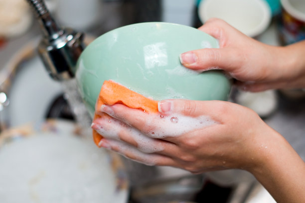 用海绵擦拭厨房里盘子的女孩的手图片下载