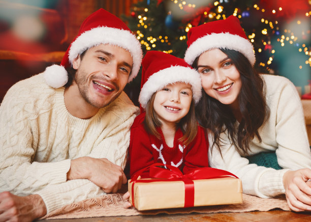 微笑的一家人躺在圣诞树旁的地板上图片下载