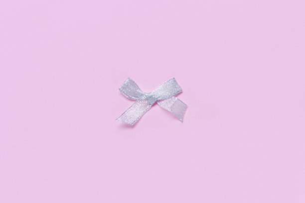 银色圣诞蝴蝶结在浅粉色的背景图片下载