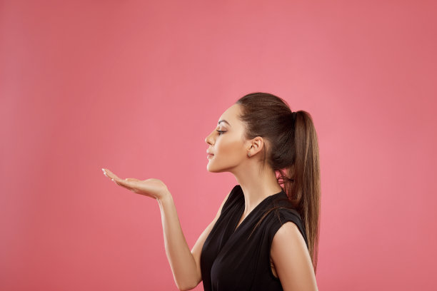 女人惊讶地笑着展示产品。美丽的女孩指着一边。展示你的广告。富有表现力的面部表情图片下载