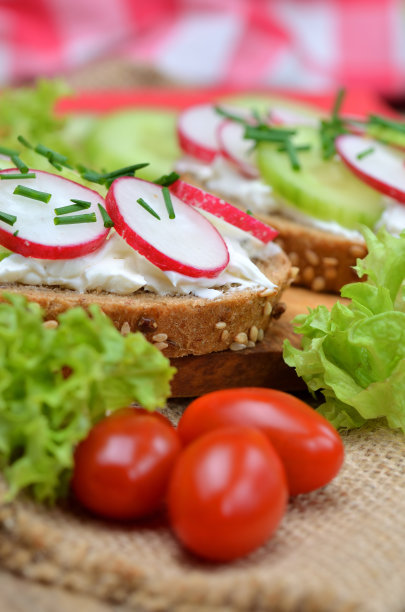 全麦谷物面包的特写，新鲜的萝卜，黄瓜和西红柿在木砧板上-健康健身早餐或零食的概念，新鲜的沙拉在背景-垂直照片图片下载