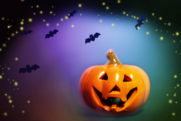微笑南瓜与黑色蝙蝠在明亮的黑色，蓝色的背景。图片下载