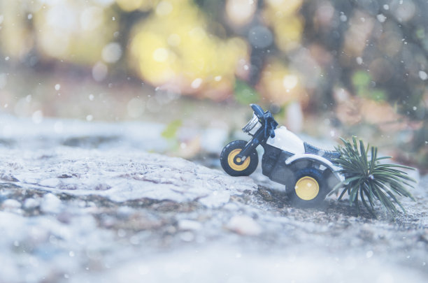 摩托车玩具载着松树在雪天翻山越岭图片下载
