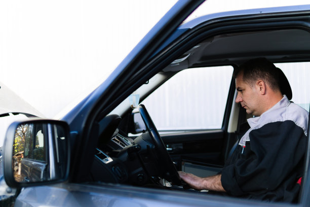 专业的汽车修理工坐在车里，用笔记本电脑检查汽车诊断。图片下载