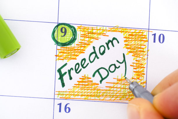 女人用绿色的笔在日历上写提醒自由日。图片下载