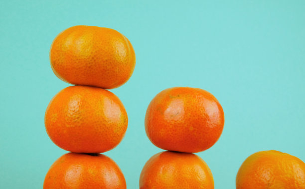 排列的成熟的橙色小柑橘，孤立在蓝绿色的背景上图片下载