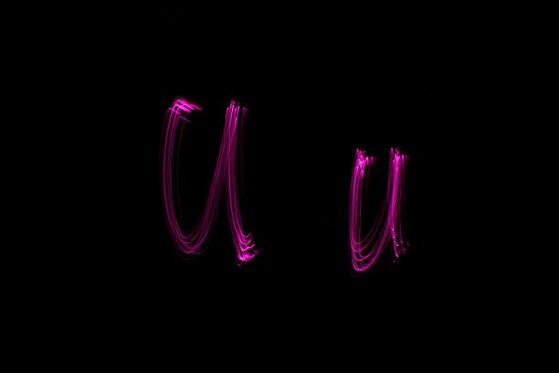 长曝光照片的字母U的大写和小写字母在充满活力的粉红色光在黑色的背景。光绘摄影。图片下载
