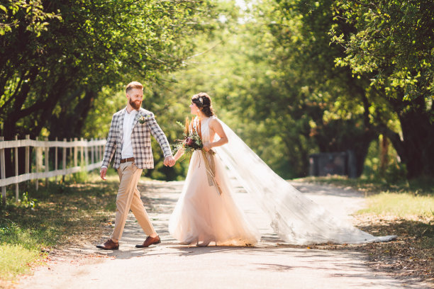 可爱的新婚夫妇木材森林。新娘和新郎，跟我来，新婚夫妇，穿着白色婚纱和面纱的女人。乡村户外爱情故事。跟随我的潮人照片。新婚夫妇手牵着手走图片下载
