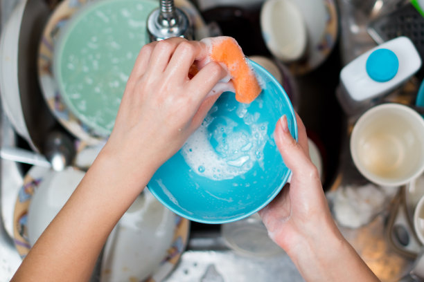 女孩在水槽里用脏盘子洗盘子图片下载