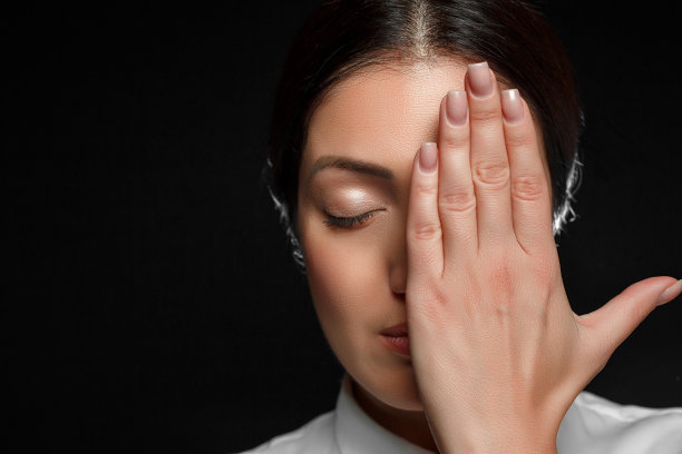 一幅亚洲女人的肖像，她穿着白色衬衫，用手遮住了她的脸，背景是黑色图片下载