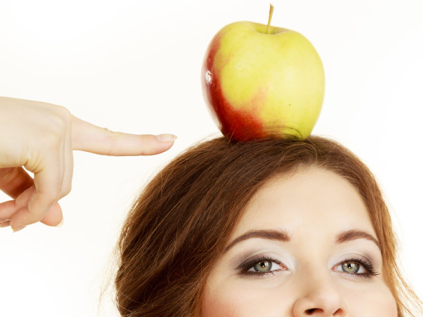 女人滑稽的女孩头上拿着苹果果图片下载